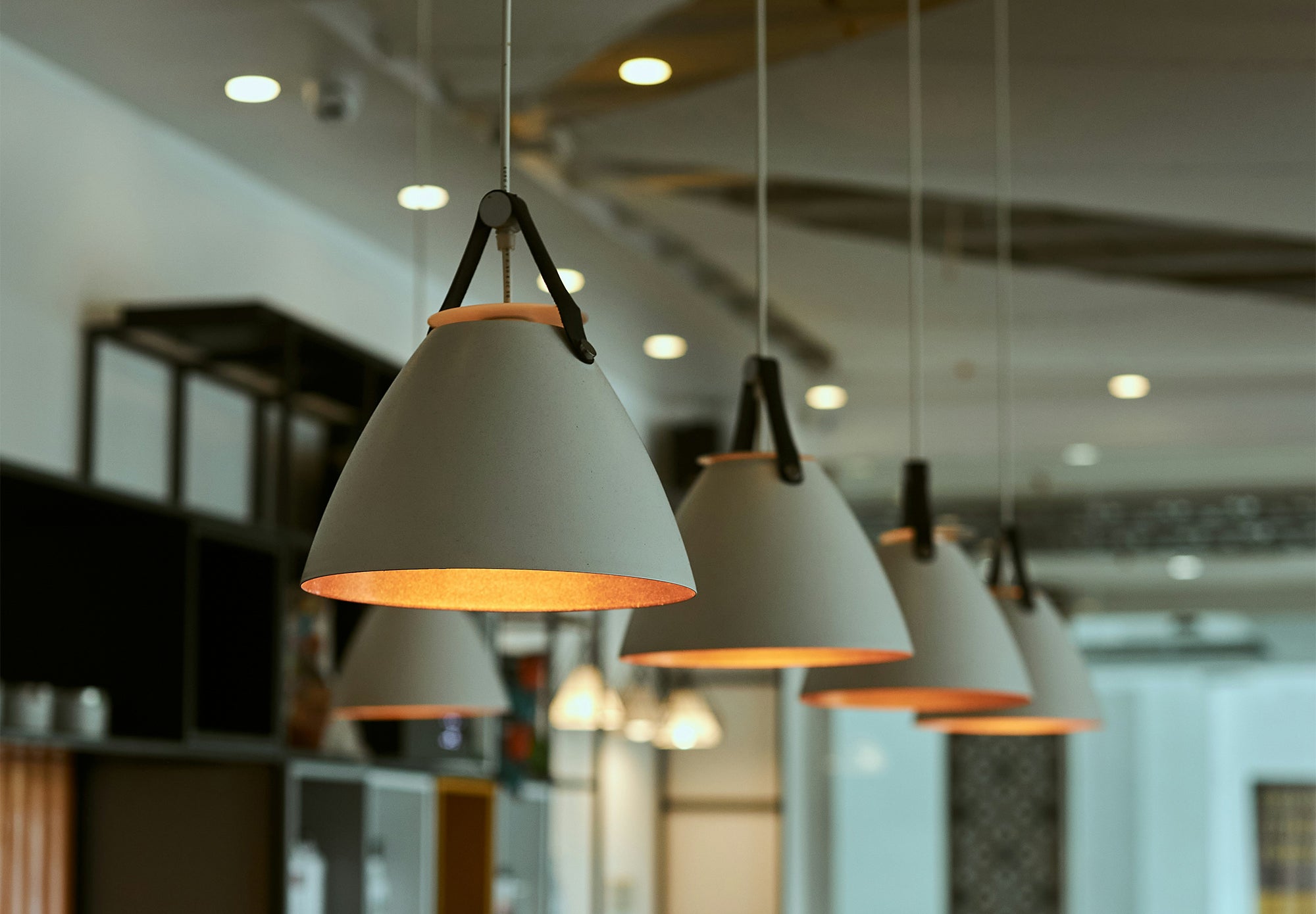 Modern grey cone-shaped hanging pendant lights with warm interior glow in a contemporary interior
