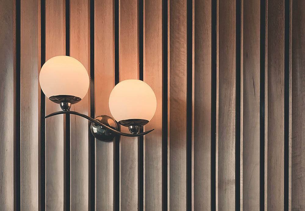 Modern wall lamp with two frosted globe shades on a slatted wooden wall