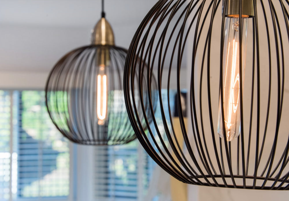 Modern black wire cage pendant lights with warm Edison bulbs
