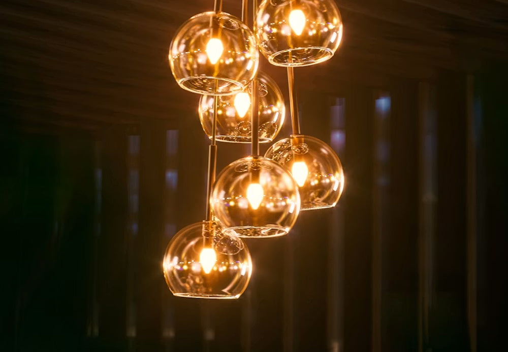 Cluster of modern glass globe pendant lights with warm glowing bulbs