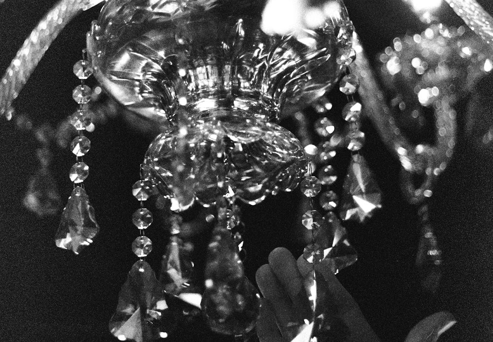 Close-up black and white photo of a luxury crystal chandelier with hanging prisms.